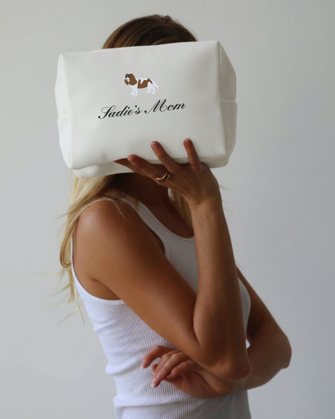 person holding white pouch with Dog Mom embroidered on it.